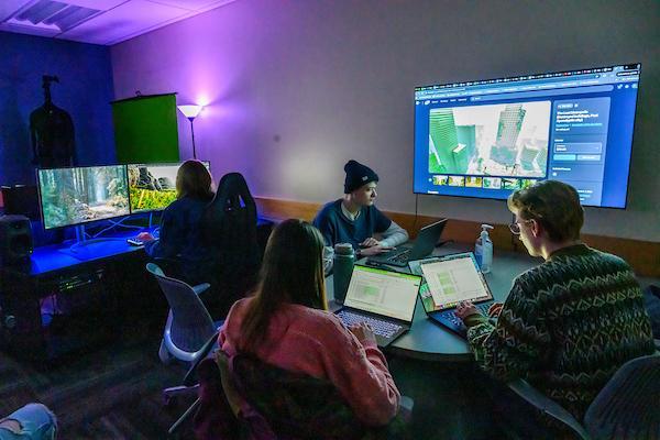 A group of students edits footage together while sitting in a visualization lab
