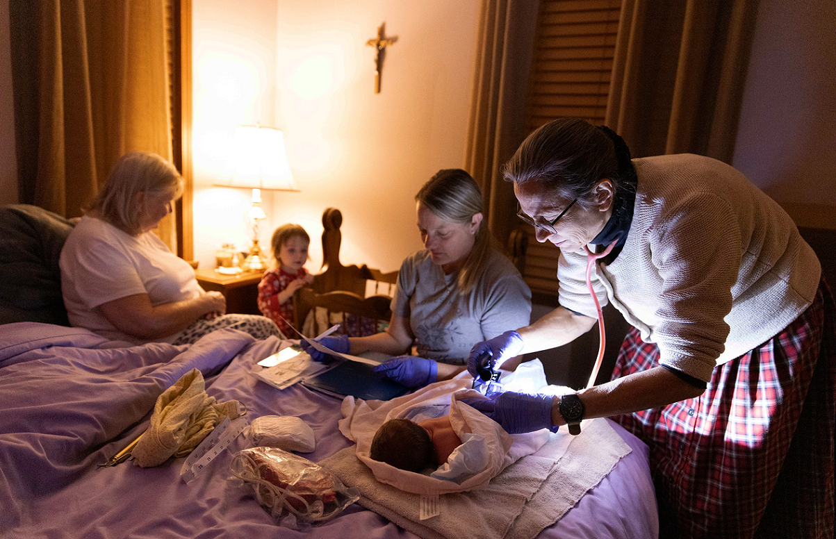 image of a midwife tending to a newborn baby in a home.