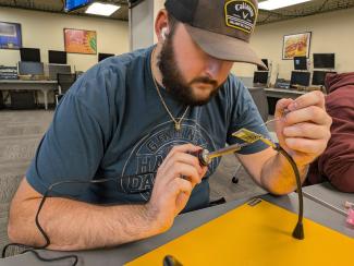 Declan Herbert, ITS Cybersecurity major, works on soldering parts to the picoballoon transmitter board.