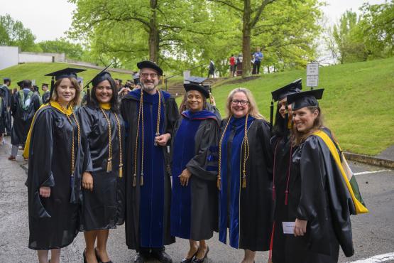 Group of graduate students pose for a photo in their academic regalia