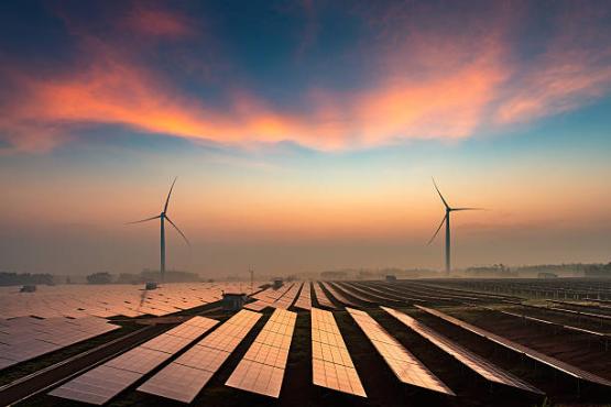Stock photo of solar panels with pink and blue clouds and windmills