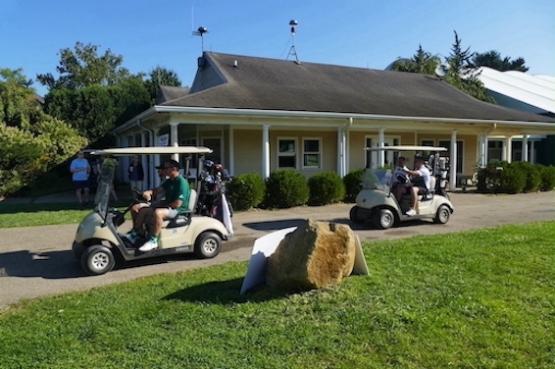 Attendees at the golfing tournament riding around in karts.