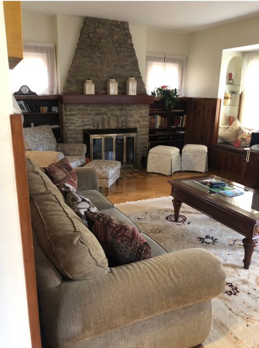 Living room with rug over wood floor, fireplace, and several windows