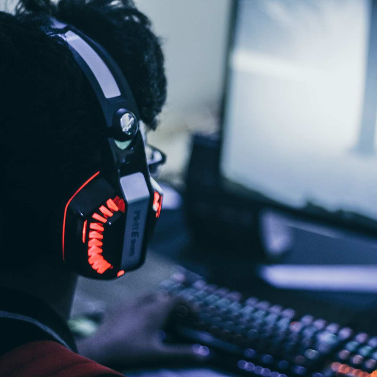 Man wears a headset while playing games on his computer.