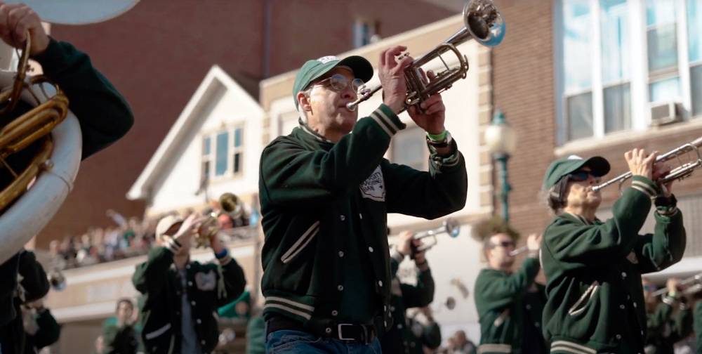 marching band alumni march in a parade playing instruments