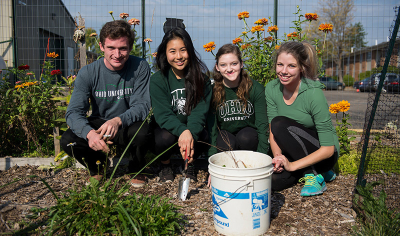 students pose for a group photo while volunteering in a garden