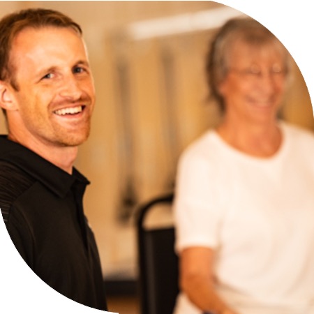 Two people smiling at an active seniors chair yoga class.