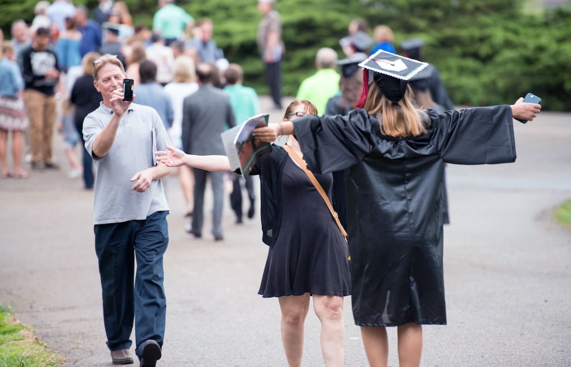 A mother and daughter hug outdoors after the daughter's graduation ceremony