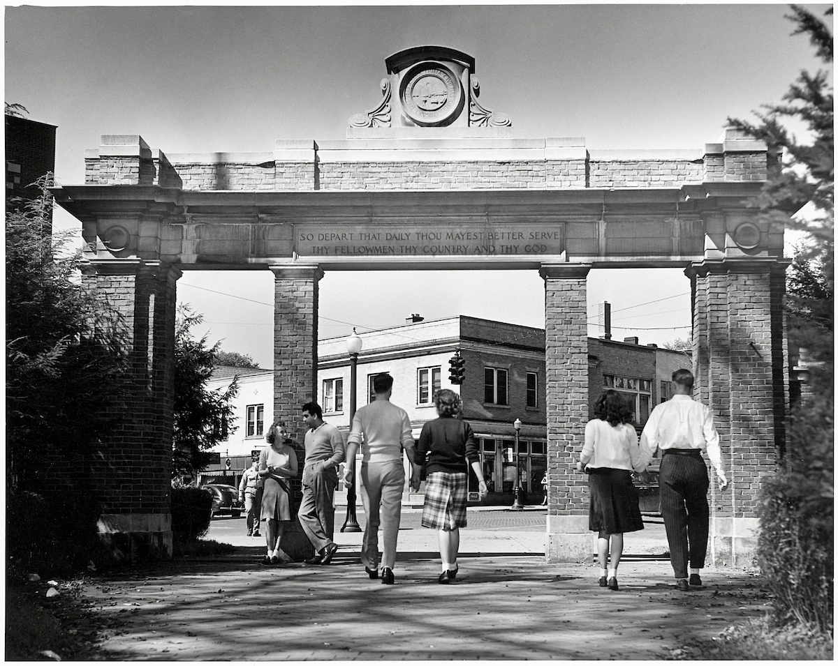 Historical photo of couple walking under the college gateway