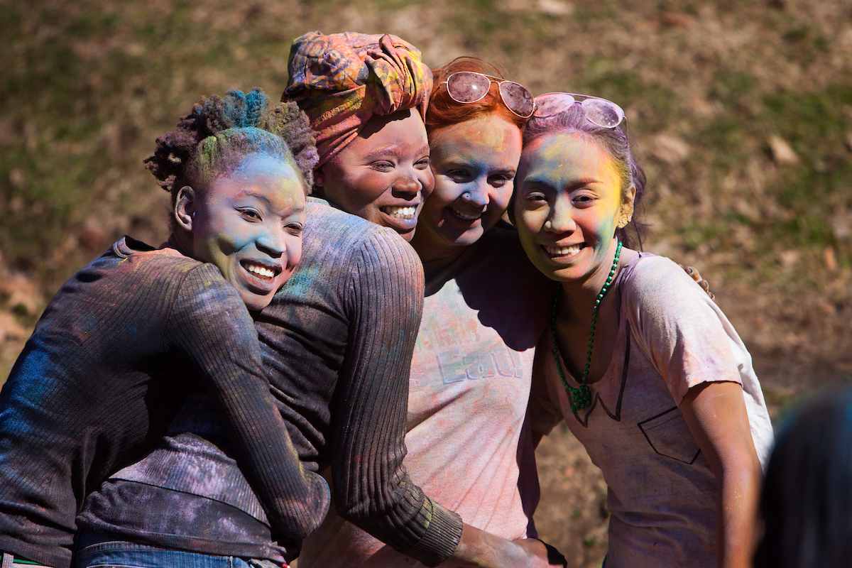 Holi week celebration with four people standing close after being covered in colorful powder