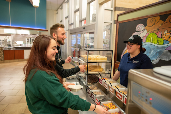 Two students talk with culinary employee behind counter at Nelson Court