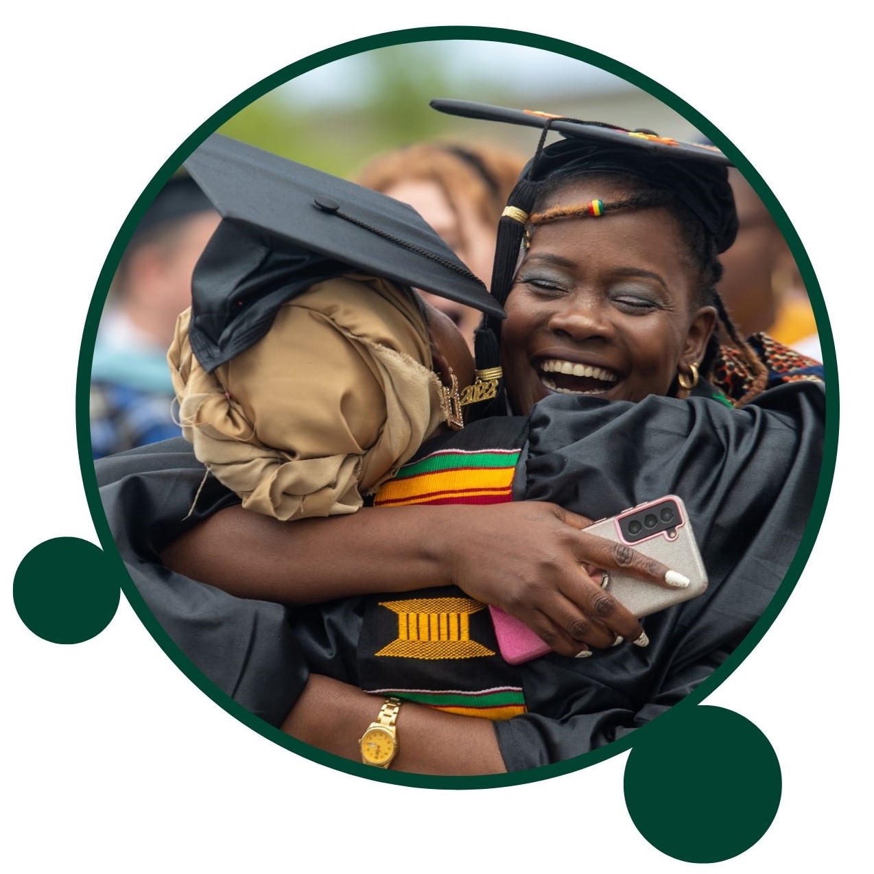 Two OHIO graduates in cap and gown hugging.