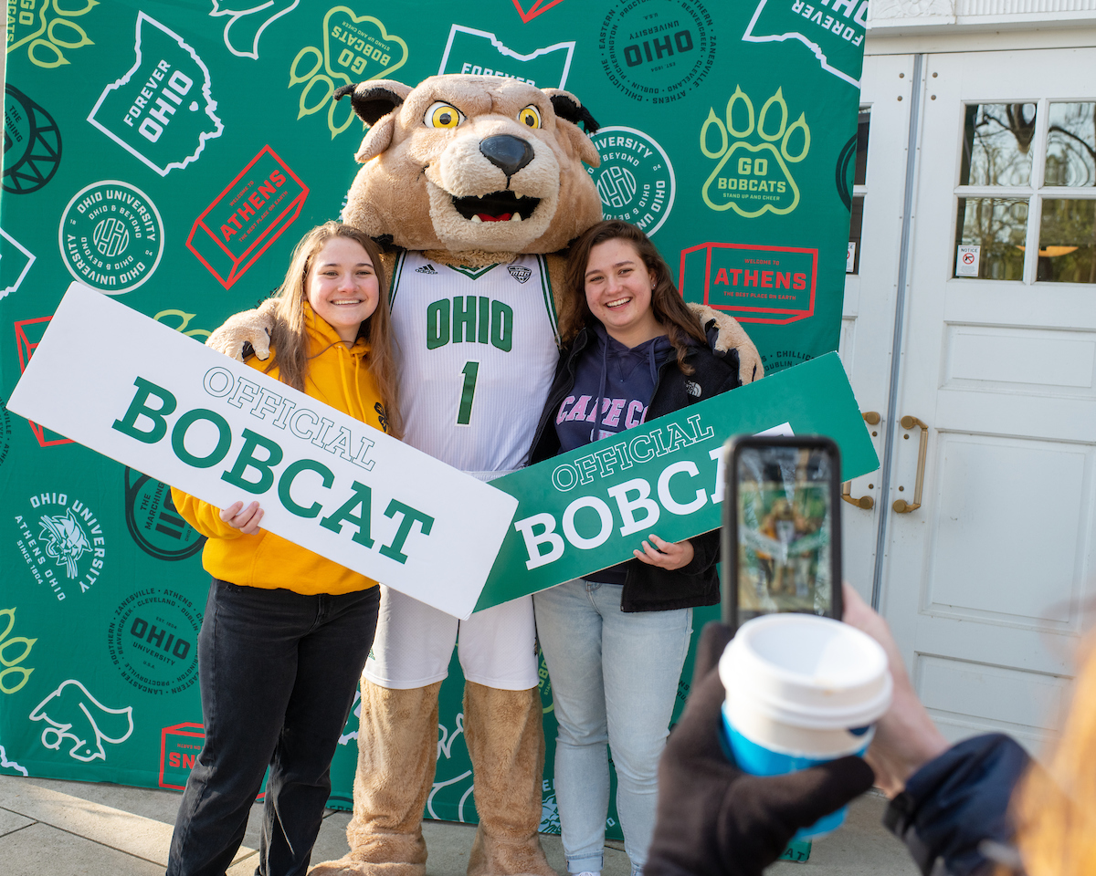 Two students holding up "I'm a Bobcat!" signs with Rufus
