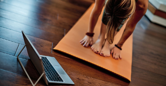 Person doing yoga with a computer nearby