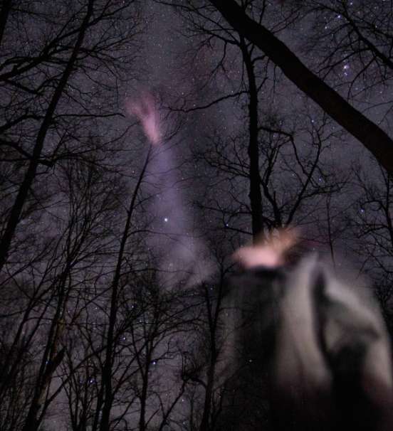 Photo of student studying night sky in winter woods