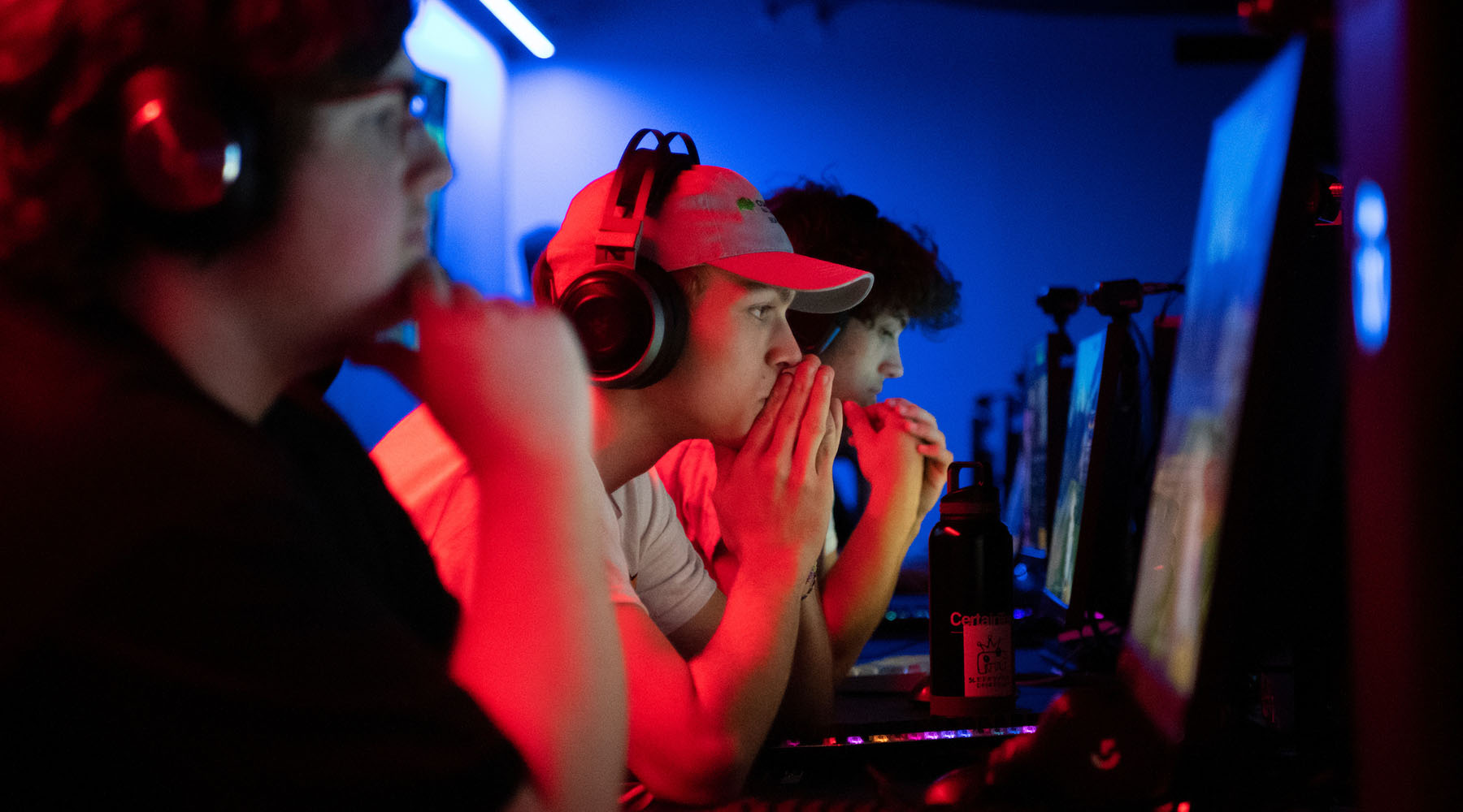 Three students work at computers in the eSports lab.