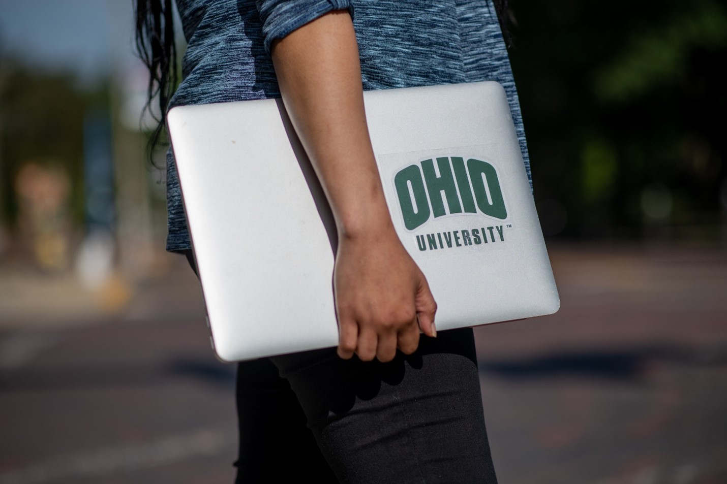 Person carrying a laptop with an Ohio University sticker on it