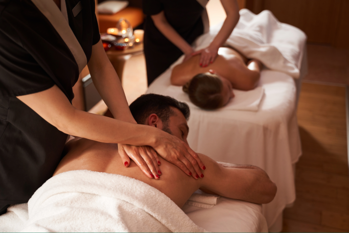 A man and a women get a couples massage together. They are both getting a massage across from each other. 