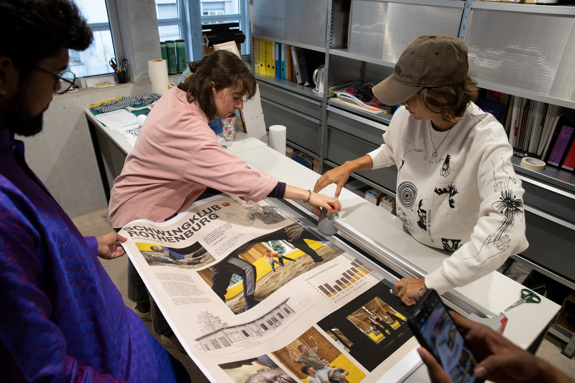Students work on cutting a freshly printed poster