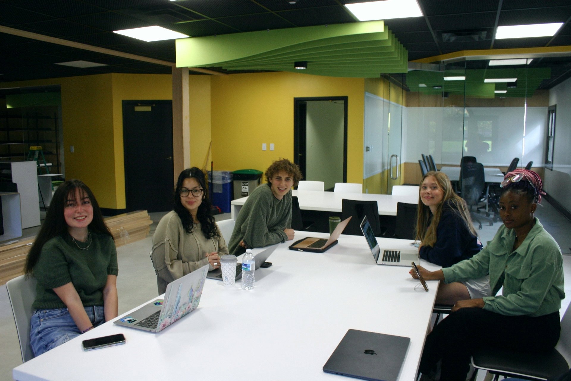 Students sit at a table working at the Next student-run advertising agency