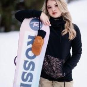 Mariko Cooper leaning on a snowboard in a black long sleeve shirt.