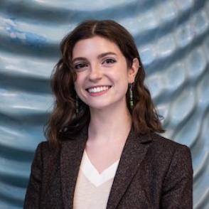 Hannah Graber smiles and stands in front of a metallic striped background
