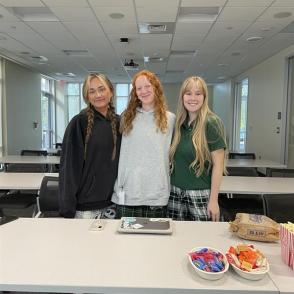 3 students at a table with candy and popcorn