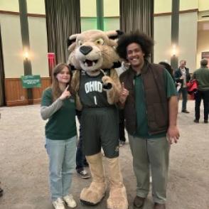 two students posing with Rufus the mascot at an event
