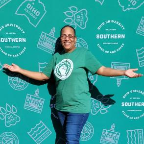 Woman with arms outstretched smiling in front of an Ohio University Southern backdrop