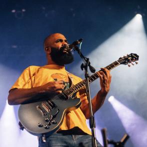 Alan Brown on stage with guitar, singing into microphone