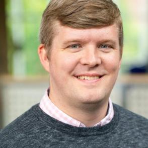 Headshot of justin fleming in collared shirt and sweater