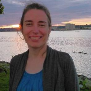Mary Kelty in front of a body of water with the sunset in the background