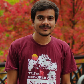 A photo of a smiling man in a red shirt in front of trees
