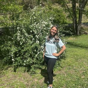 Woman standing outdoors next to flowering bush
