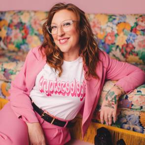 Woman in pink suit and glasses smiling