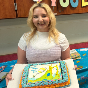 woman smiling and holding cake with dr. suess image