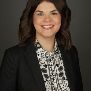 image of a woman wearing a dark suit jacket smiling with a black and white shirt and dark hair