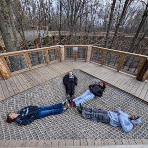 Students lie on a rope net in the canopy park