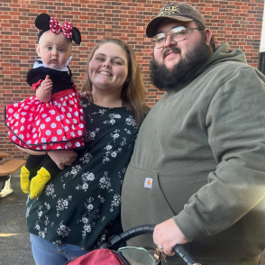 Nursing grad McKayla stands with child in Minnie Mouse costume and man