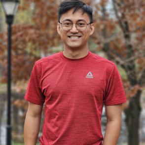 A photo of a smiling man in front of a brown tree