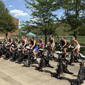 big group of students participate in the cycling class outside