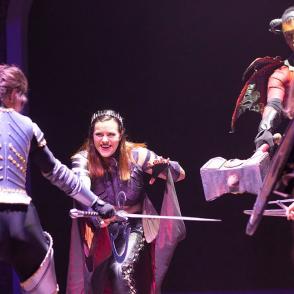 students dressed in medieval costumes perform a play at the university theater 