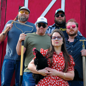 Members of Sasha Colette & the Magnolias standing in front of a barn holding tools