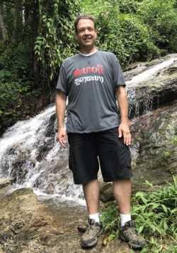 Member standing in the woods on a hiking slope