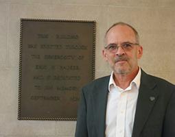 Prof. William Condee stands in front of mounted wall plaque