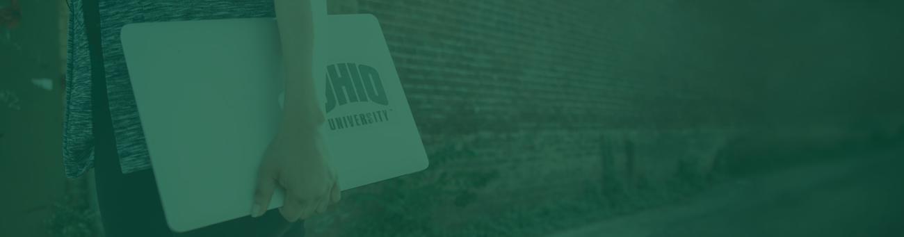 OHIO student carries a laptop outside with an Ohio University sticker on it
