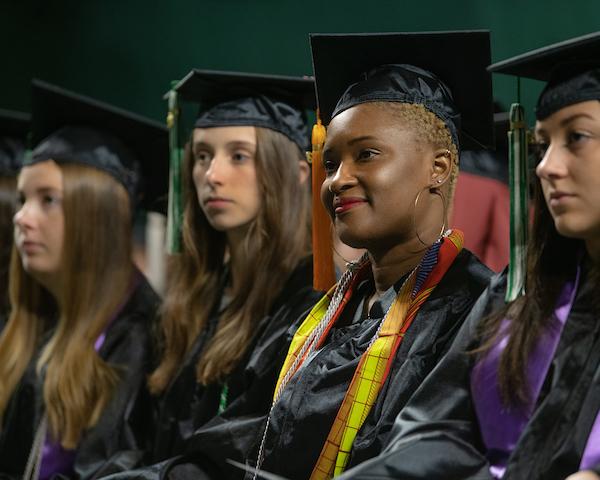 Students smile while wearing their caps and gowns during Commencement