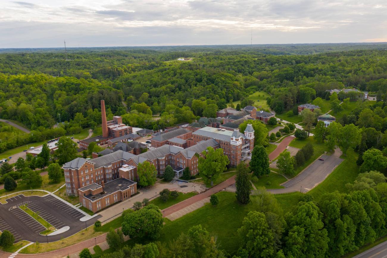 An aerial view of The Ridges brick building, surrounded by rolling hills and trees