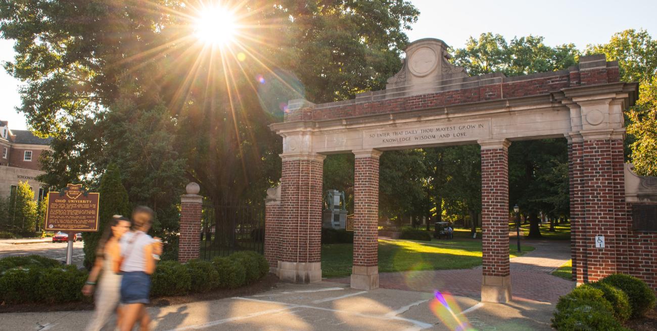 Two people walking through College Gate.