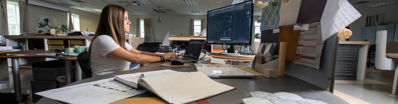 A student works at a desk on a project.